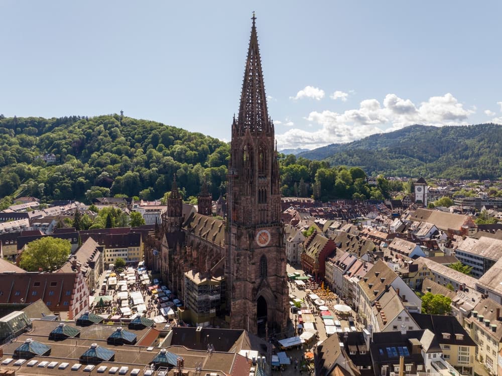 Luftaufnahme des Freiburger Münsters mit Altstadt und bewaldeten Hügeln